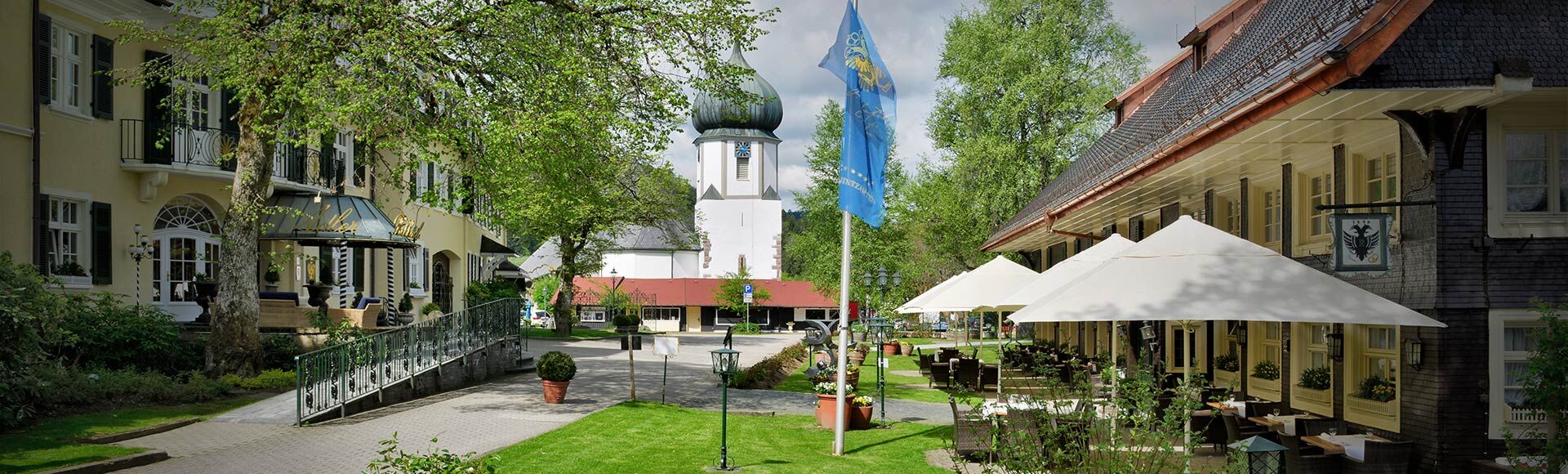 Blick: links Eingang des Hauptgebäudes, Mitte Kirche, rechts Terrasse mit Schwarzwaldhaus